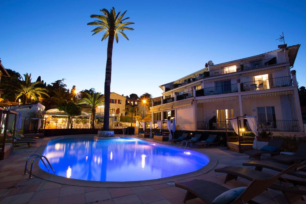 费拉角圣让Boutique Hotel & Spa la Villa Cap Ferrat的一座建筑前的游泳池,里面种着棕榈树