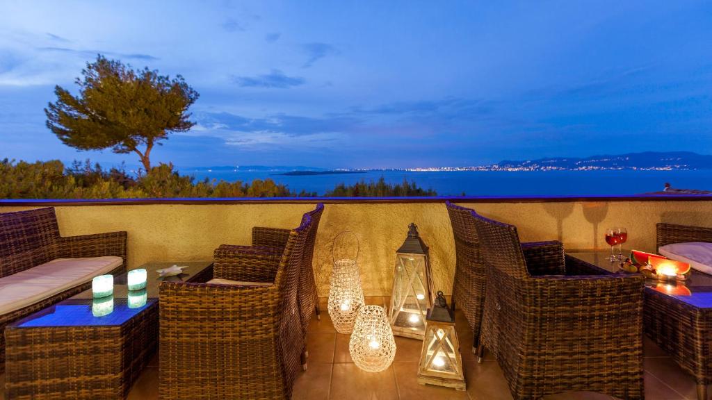 迈加洛丘里艾巴蒂斯酒店的阳台配有藤椅和带蜡烛的桌子。