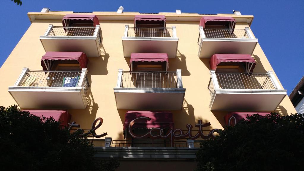 里米尼Hotel Capitol的带阳台和粉红色屋顶的高楼