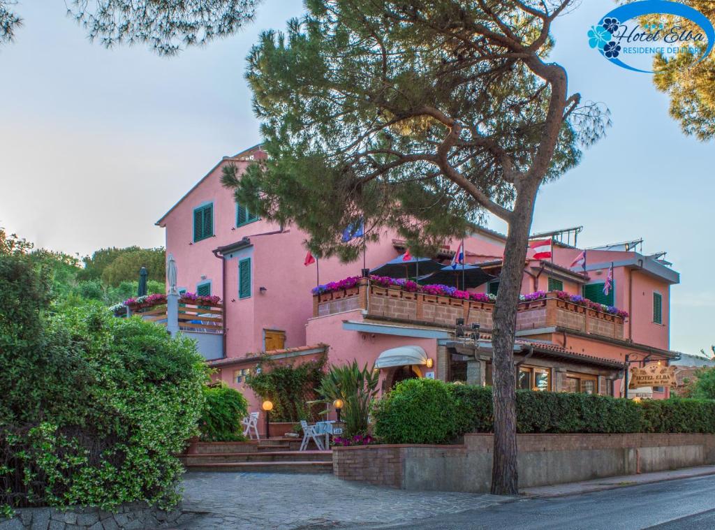 坎普码头Hotel Elba的前面有一棵树的粉红色房子