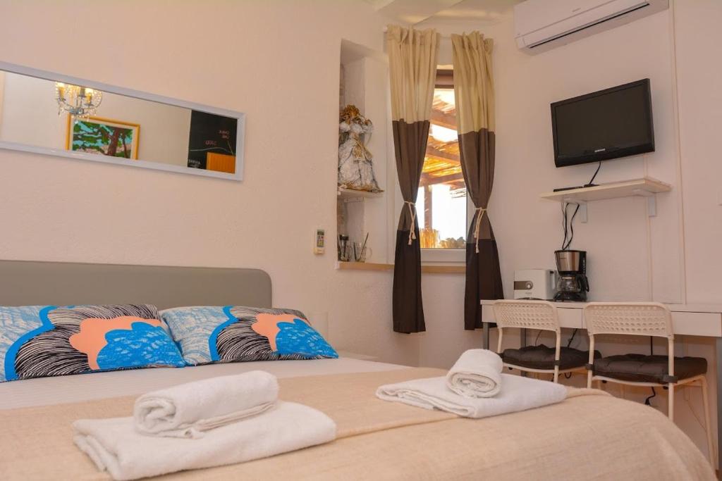 杜布罗夫尼克Apartment and room Sveti Jakov的一间卧室配有一张床、一台电视和一张桌子