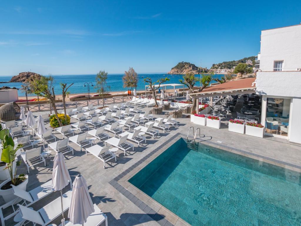 滨海托萨金色之海蒙努达酒店的一座带游泳池和椅子的酒店,以及大海