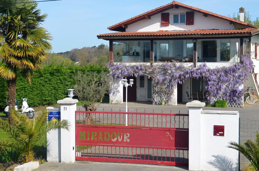 塔尔诺斯Maison d'hôtes MIRADOUR的一座带红色围栏的紫色花圈的房子