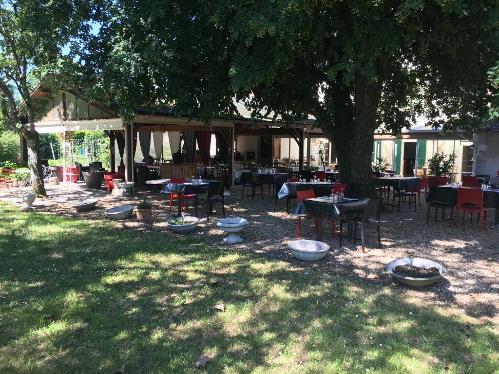 Saint-Aigulin迪特文艺术酒店的树下设有桌椅的餐厅