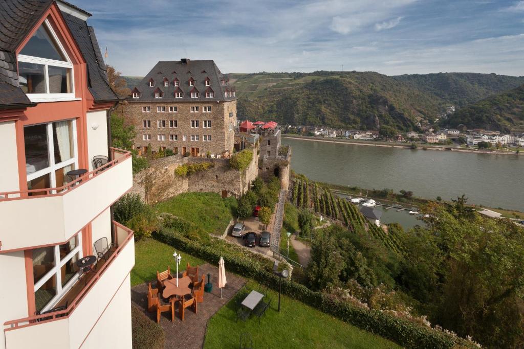 圣戈阿尔Hotel Schloss Rheinfels的水体旁小山上的城堡