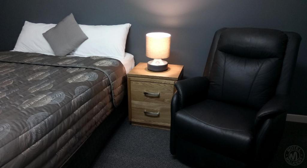 Millicent米利森特汽车旅馆的一间卧室配有一张床、一把椅子和一盏灯