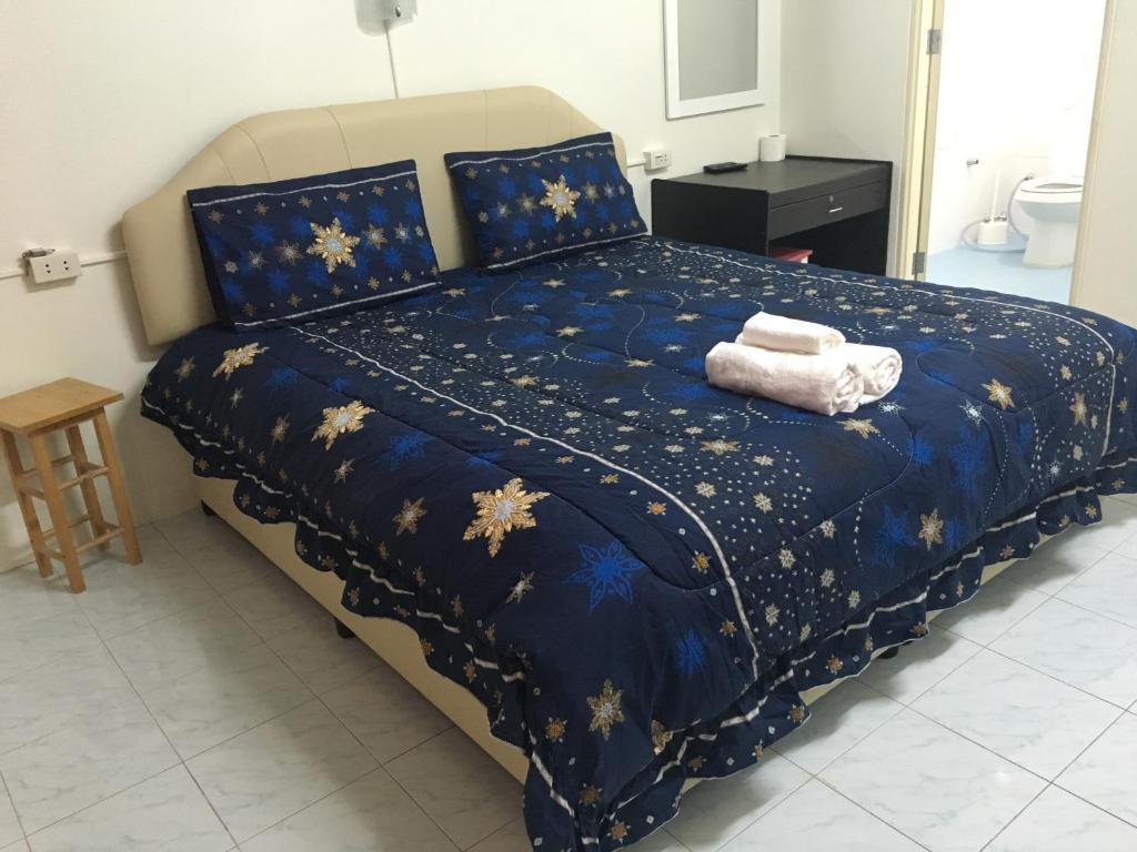 班佩幸福家园旅馆的一张带蓝色棉被的床,上面有两条毛巾