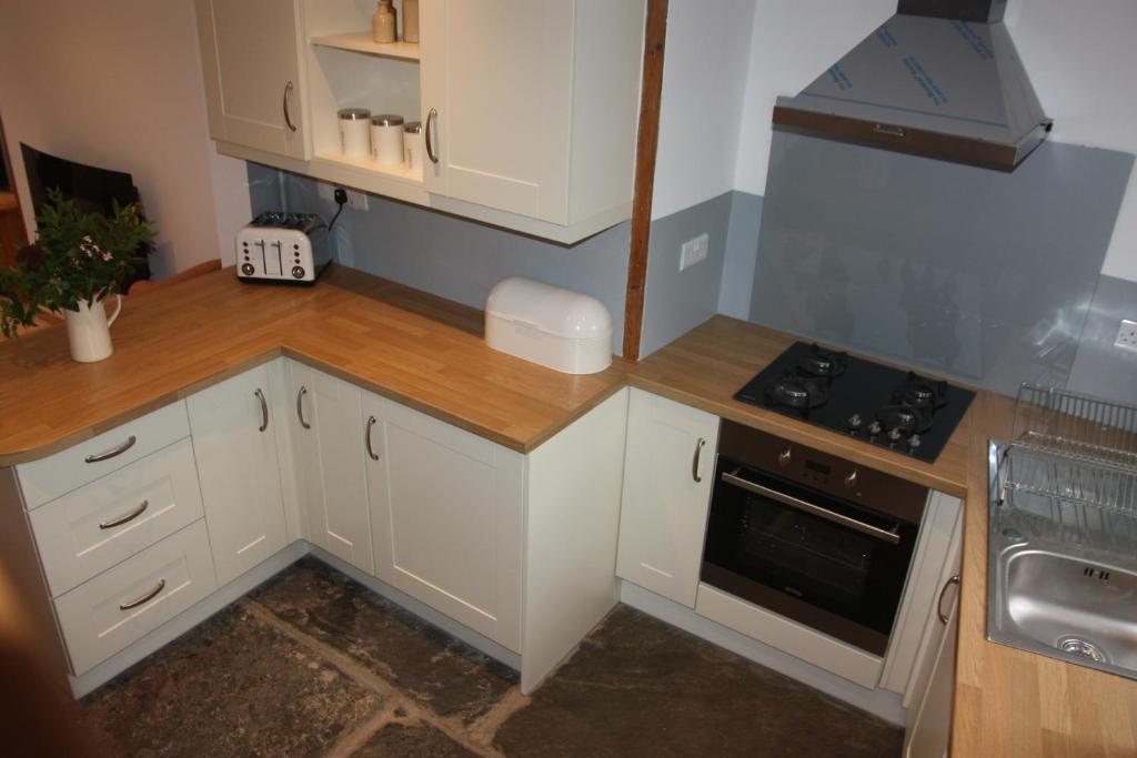 赖厄德Delfryn Cottage的小厨房配有白色橱柜和炉灶。
