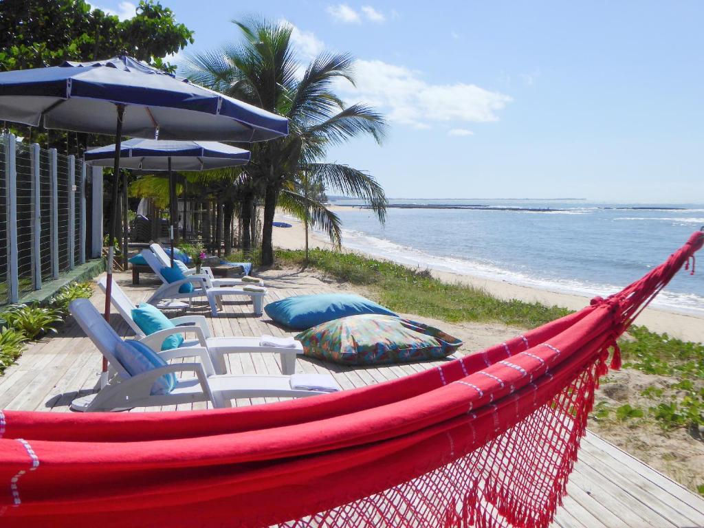 阿拉亚尔达茹达Ouro Sobre Azul Apart Hotel的海滩上的吊床,配有椅子和遮阳伞