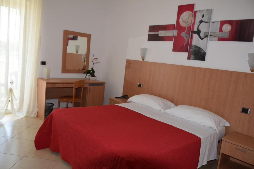 维耶斯泰马焦雷酒店的一间卧室配有一张带红色毯子和镜子的床