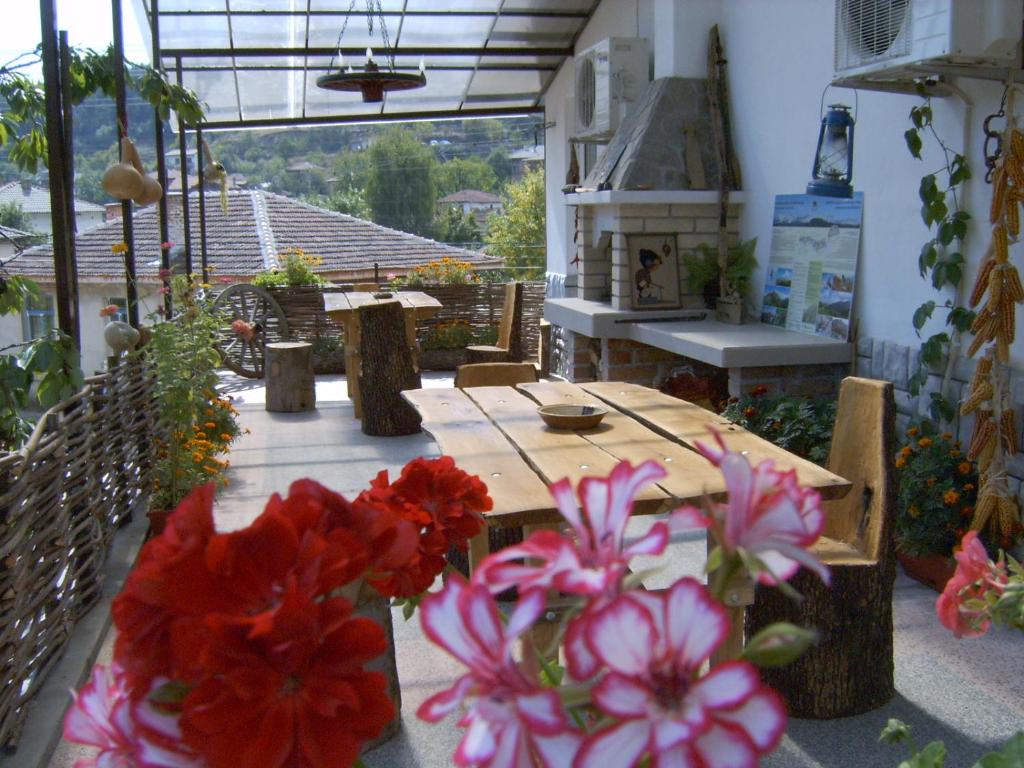 卡洛费尔Georgievi Guest House的露台上的一张桌子上放着红色和粉红色的花朵