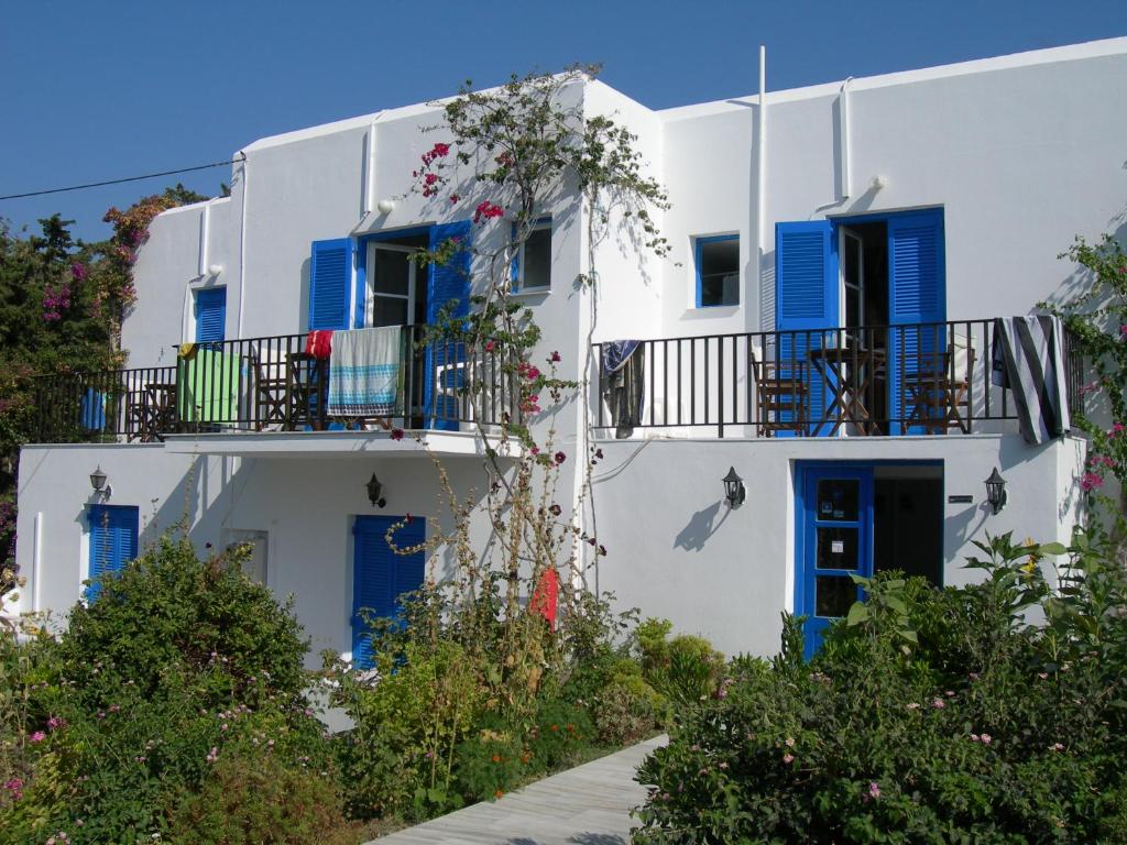 帕罗奇亚Bizas Rooms & Studios的白色的建筑,设有蓝色百叶窗和阳台