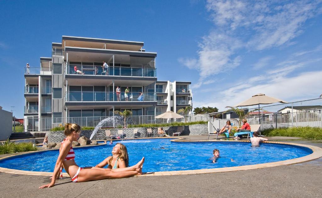 奥霍普海滩欧霍普海滩度假酒店的两个女孩坐在度假村的游泳池里