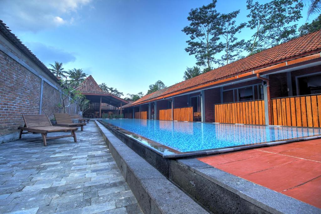 婆罗浮屠婆罗浮屠瓦伊德酒店的一座游泳池,旁边设有长凳