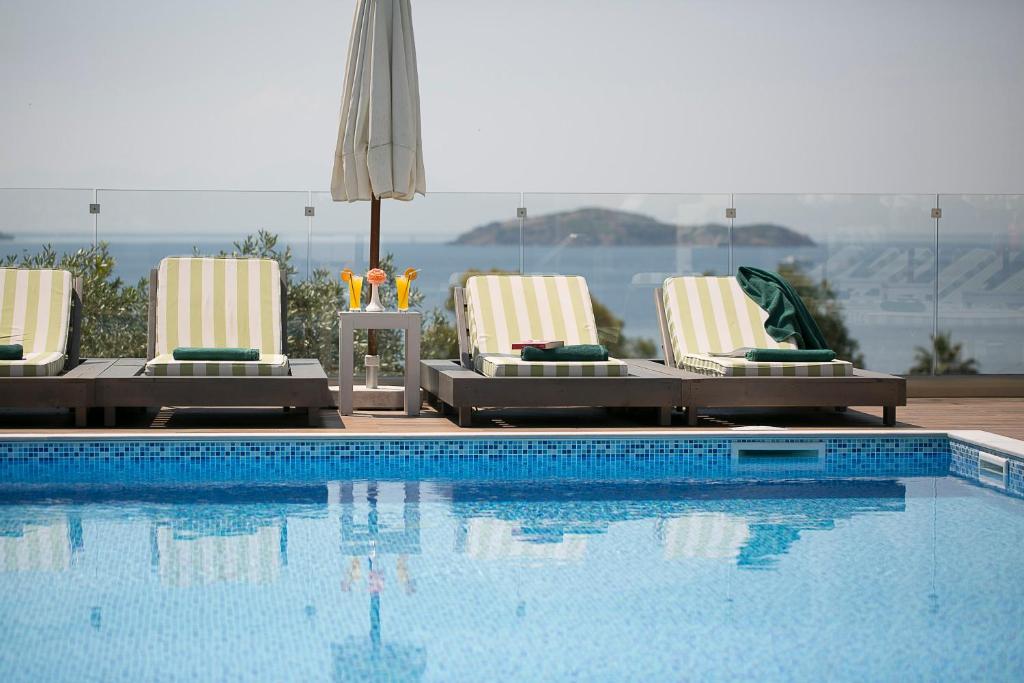 梅加利阿莫斯Irida Aegean View, Philian Hotels and Resorts的一个带2把躺椅和遮阳伞的游泳池