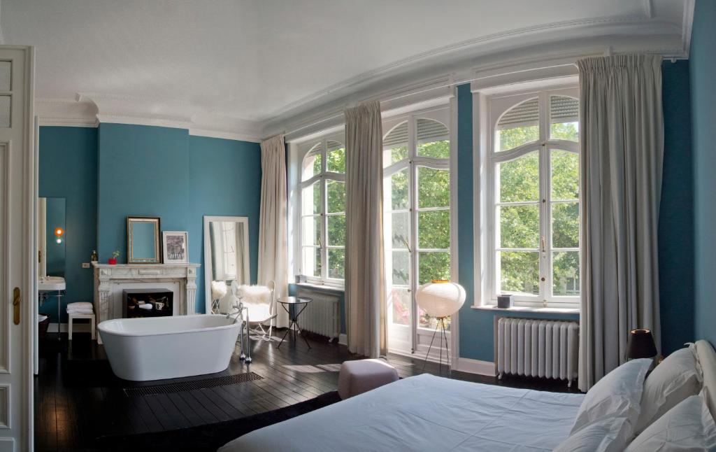 布鲁塞尔Appartement Chic的一间带浴缸的浴室和一间带蓝色墙壁的卧室