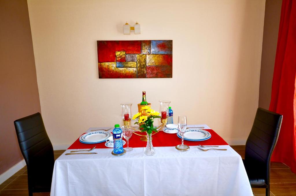 KakamegaLamanis Haven的一张带白色桌布和一瓶葡萄酒的桌子