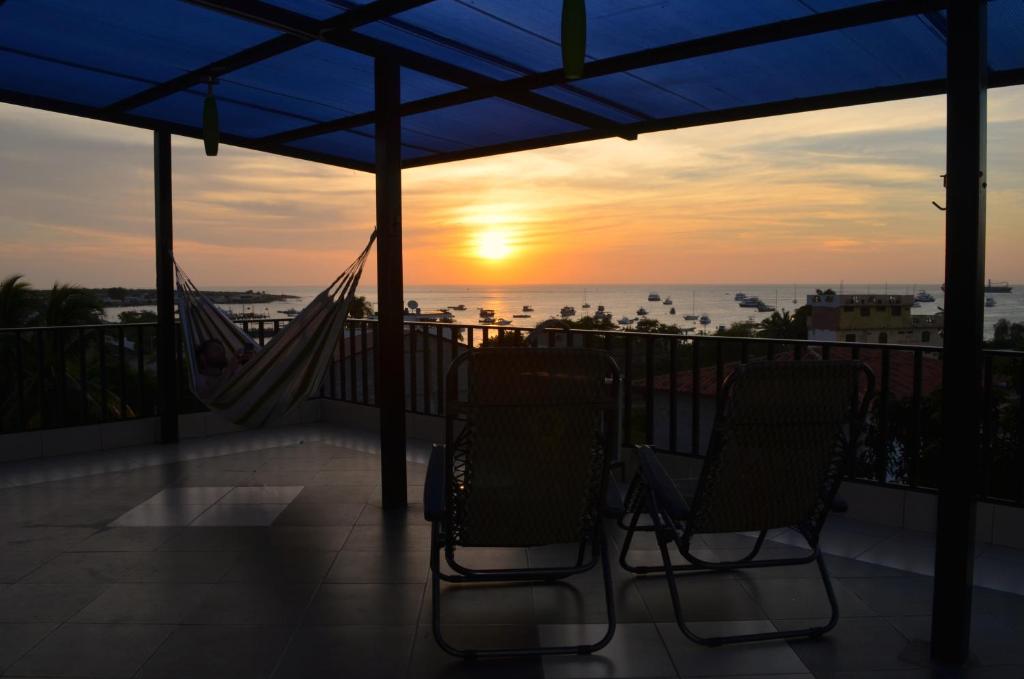 巴克里索莫雷诺港海豚之家酒店的日落时分带2把椅子和吊床的阳台