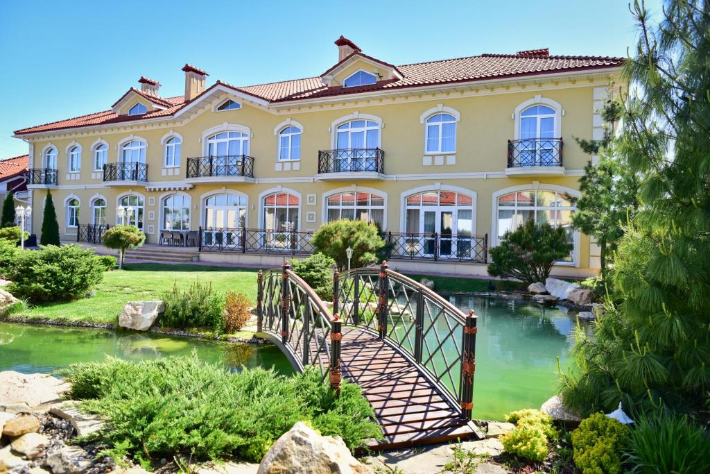 文尼察Hotel Villa Venice的一座黄色的大建筑,有一座河上的桥梁