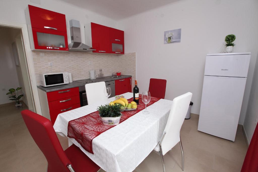 斯普利特Apartman Seaside Paradise的一间带桌椅的厨房和一间带红色橱柜的厨房