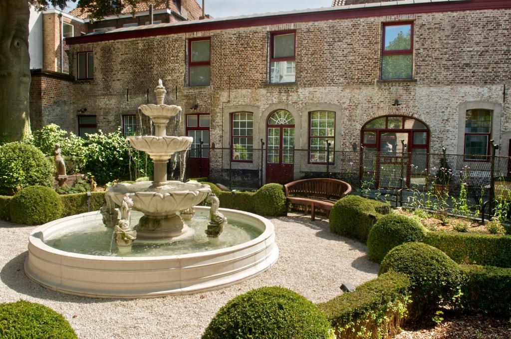 布鲁日Hotel Jan Brito的一座花园中的喷泉,位于一座建筑前
