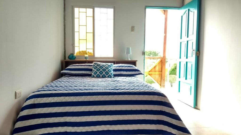 马查利亚Guest House Villa Machalilla的一间卧室配有一张带蓝白条纹毯子的床