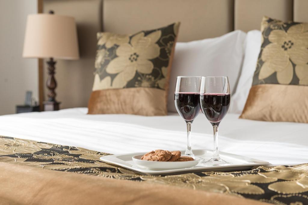基督城金星汽车旅馆的床上有两杯葡萄酒和一盘食物