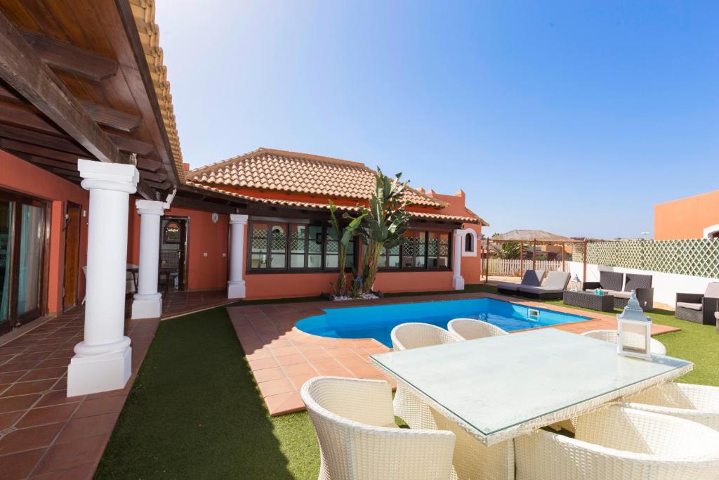 科拉雷侯Villa Corralejo Beach的一个带桌椅的庭院和一个游泳池