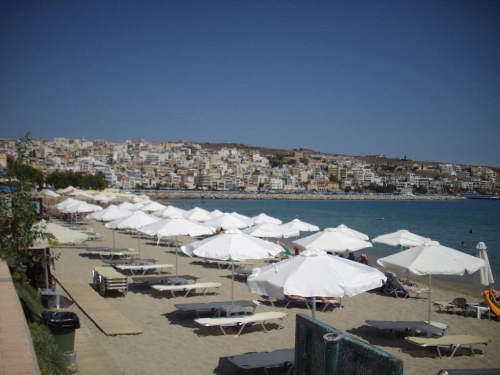 锡蒂亚Anna Villa的海滩上设有白色的遮阳伞和椅子,还有水