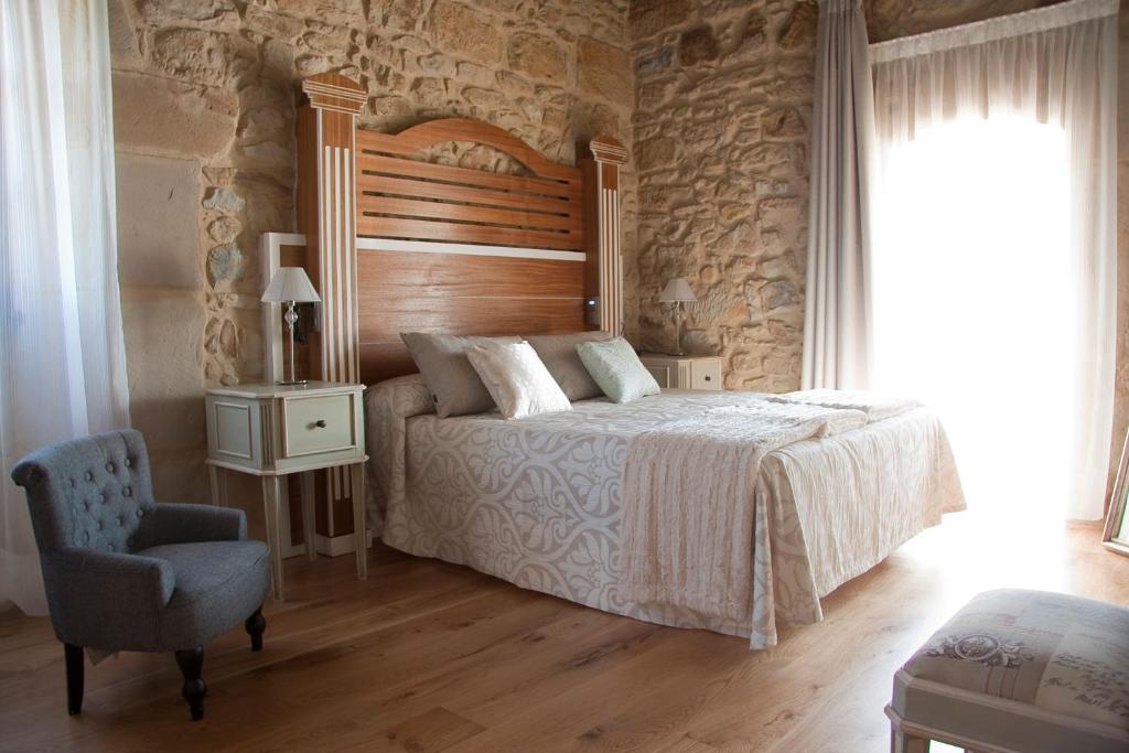 Beranga拉托德洛斯岛及Spa旅馆的一间卧室配有一张带木制床头板和椅子的床。
