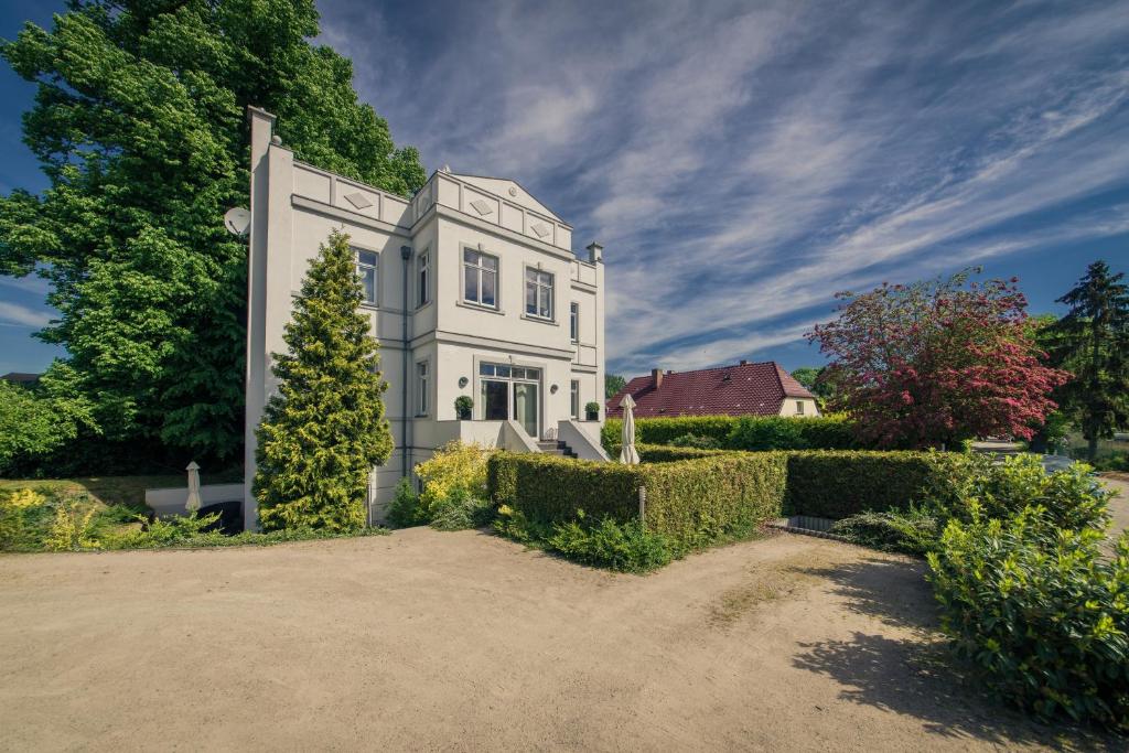 KrumminGutshaus Krummin Usedom的一座大白色房子,有树木和灌木