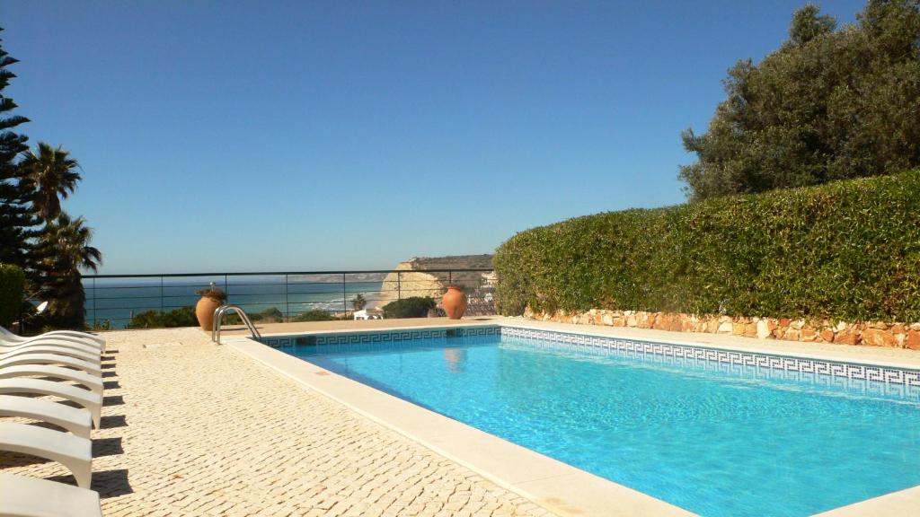 拉戈斯维温达索尔玛酒店的一个带椅子的游泳池,背景是大海