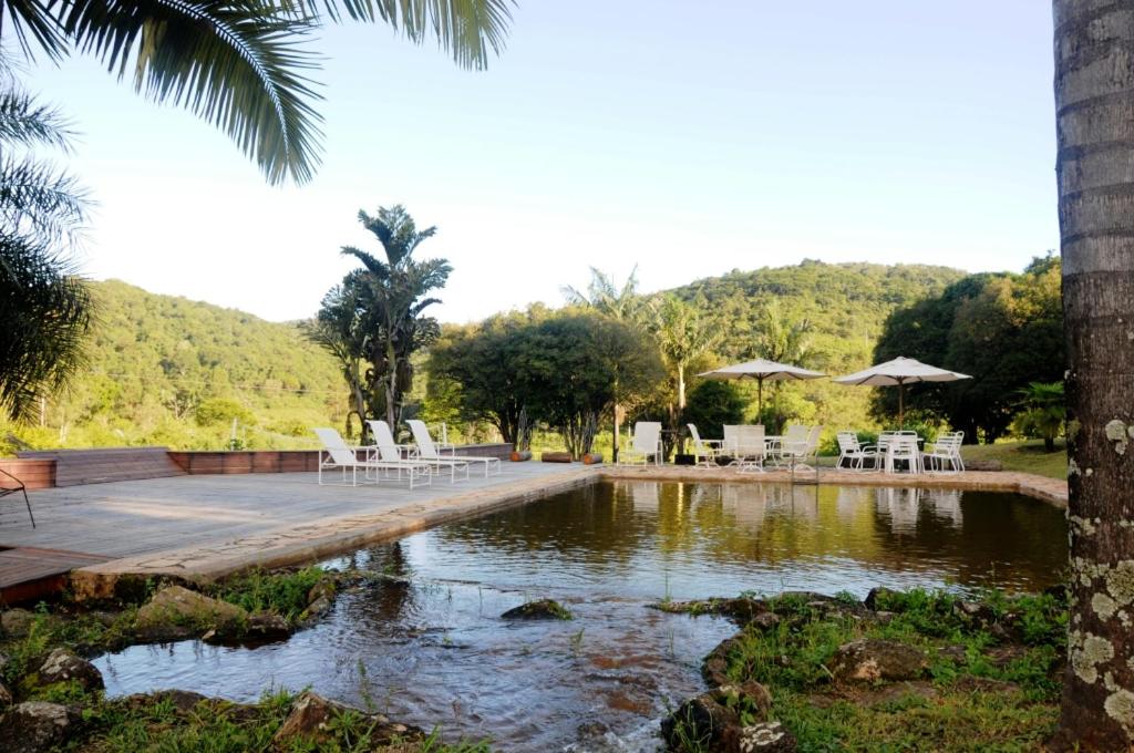 伊塔比里图Hotel Fazenda Caco de Cuia的一个带白色桌椅的游泳池和一个湖泊