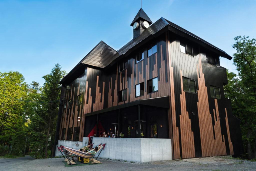 白马村Hotel Villa Hakuba by Hakuba Hospitality Group的一座大型木制建筑,顶部设有钟楼