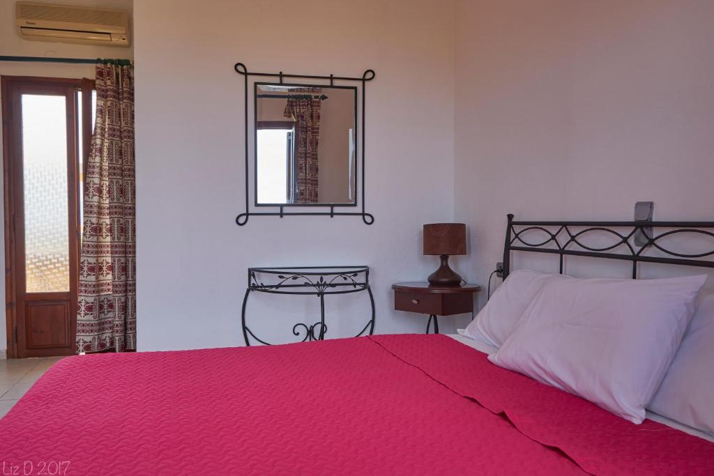 锡蒂亚蒂米特拉公寓酒店的一间卧室配有一张带红色毯子和镜子的床