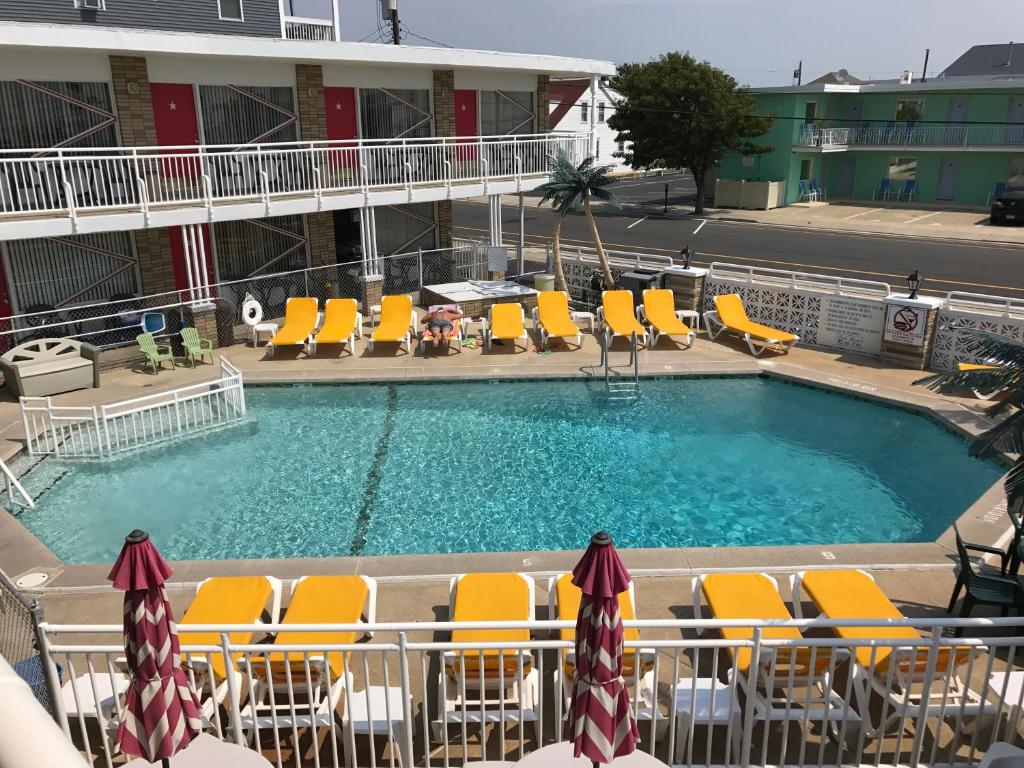 怀尔德伍德Starfire Motel的一座游泳池,设有黄色的躺椅