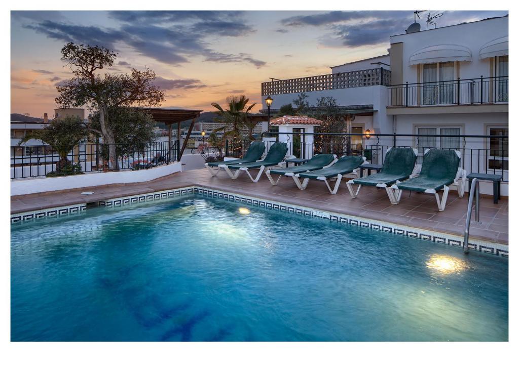 罗列特海岸妮娜伊斯酒店的一座带椅子的游泳池以及一座建筑
