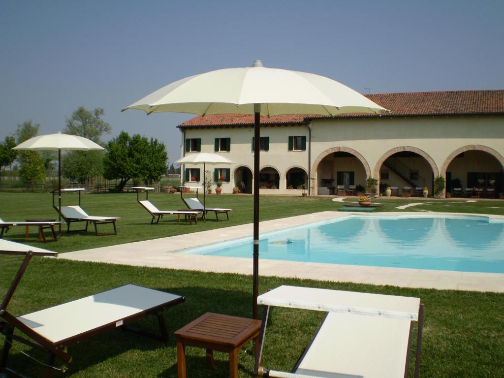 圣比亚焦迪卡拉尔诗人隐修所酒店的一座带椅子和遮阳伞的游泳池位于大楼旁
