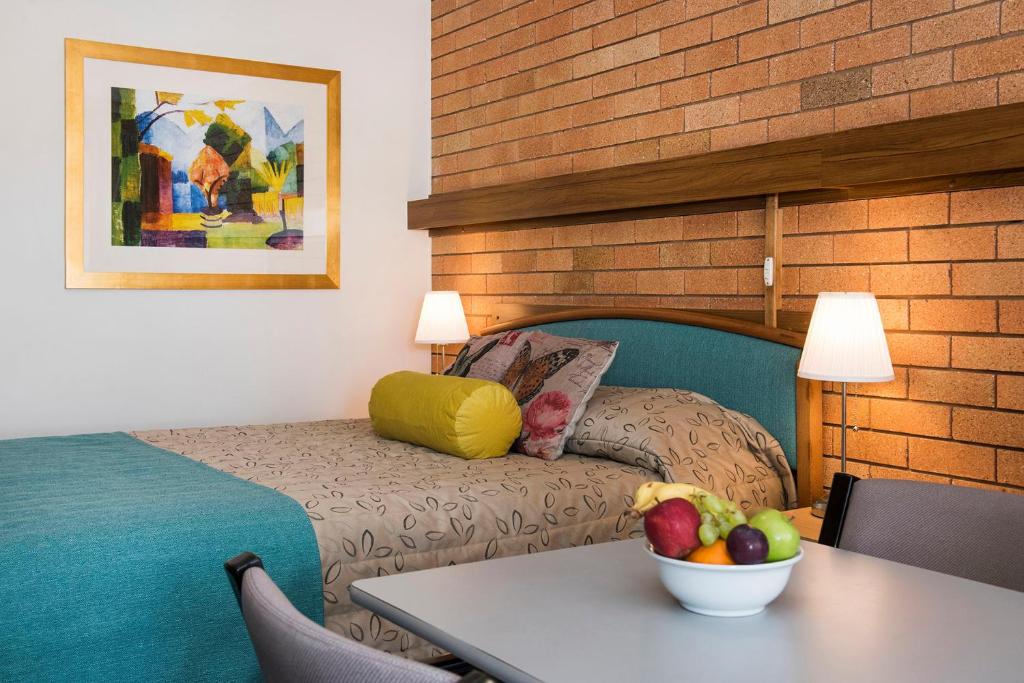 马奇尼格娜汽车旅馆的一间房间,配有一张床和一张桌子,还有一碗水果