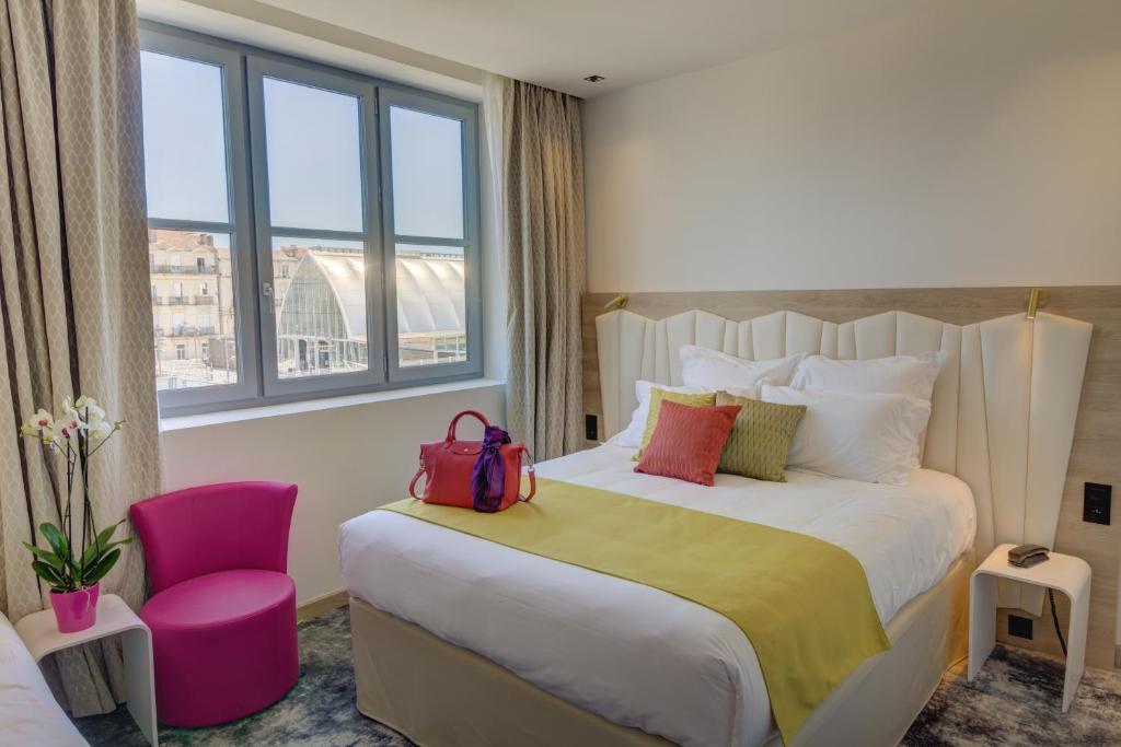 蒙彼利埃圣罗奇喜剧贝斯特韦斯特优质酒店的酒店客房,配有一张床和一张粉红色的椅子