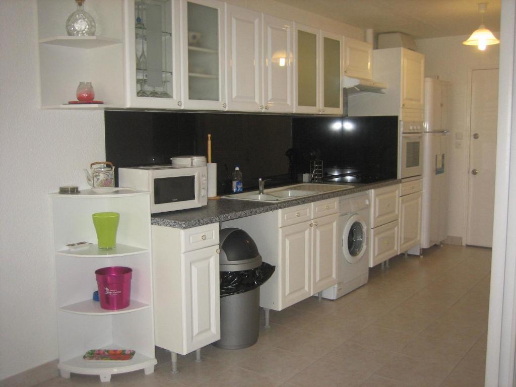 东方湾东方湾27公寓的厨房配有白色橱柜、水槽和微波炉