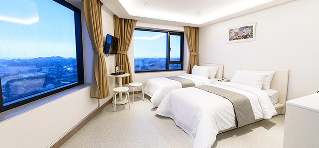 西归浦市瑞兹翁酒店的酒店客房设有两张床和大窗户。