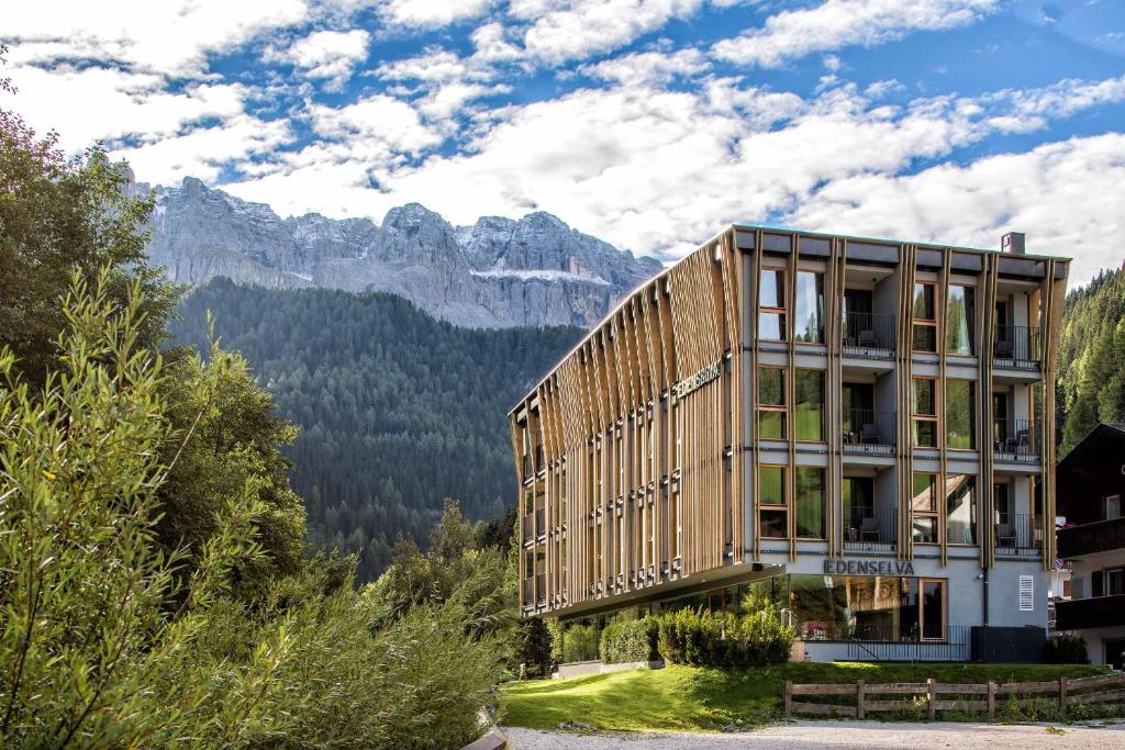 塞尔瓦迪加尔代纳山谷Mountain Design Hotel EdenSelva的一座以山脉为背景的木制建筑