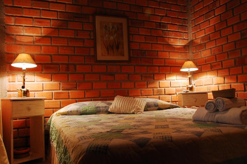 里韦拉博斯克波萨达酒店的一间卧室设有砖墙、一张床和两盏灯