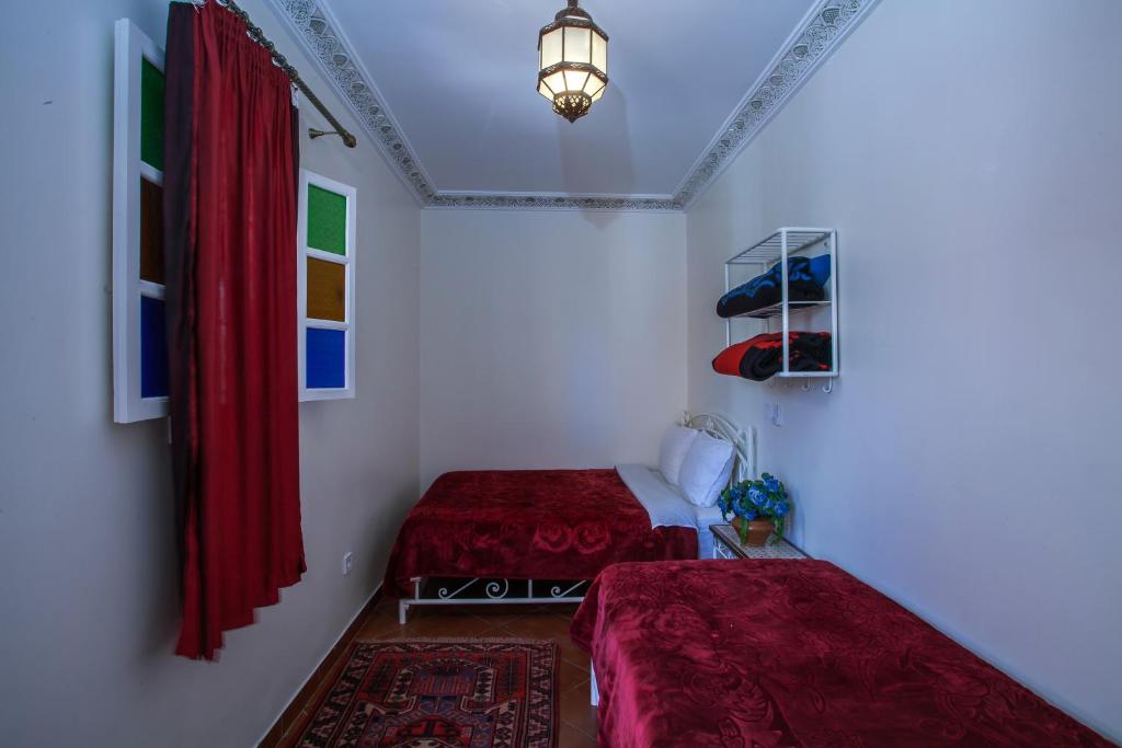 马拉喀什斋图内酒店的配有红色窗帘和灯的客房内的两张床