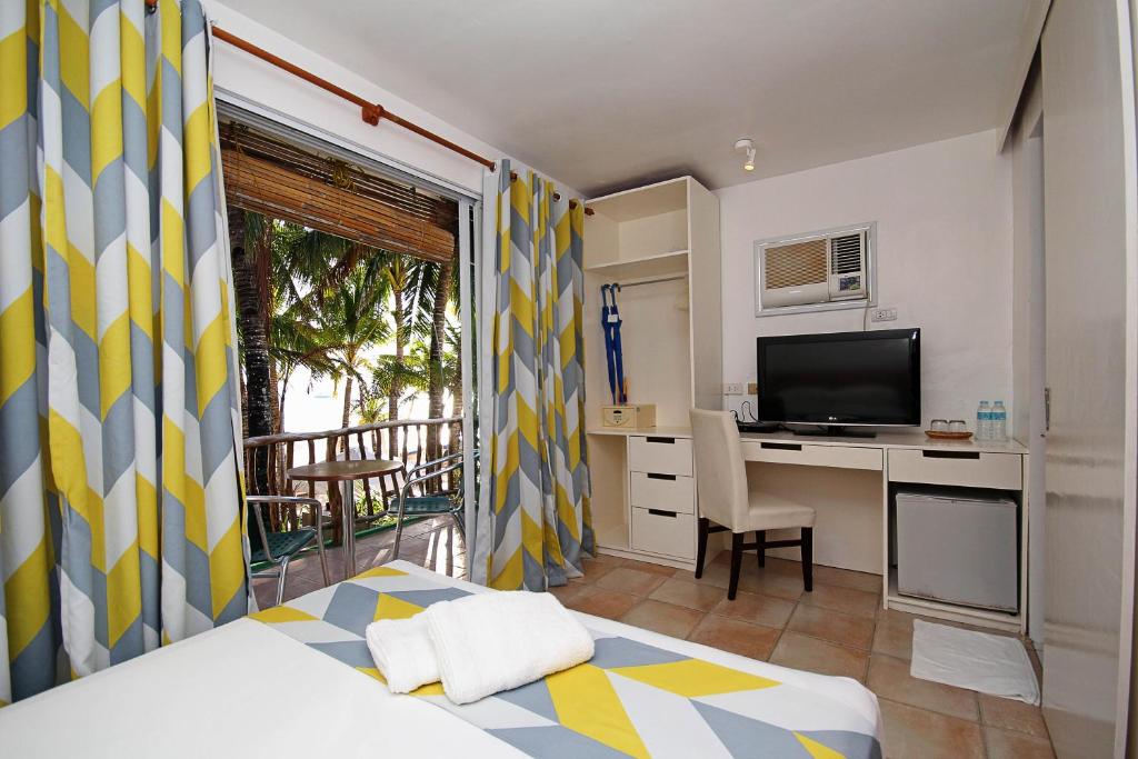 长滩岛蓝色海浪沙滩小屋住宿加早餐旅馆的一间卧室配有一张床和一张书桌及电视