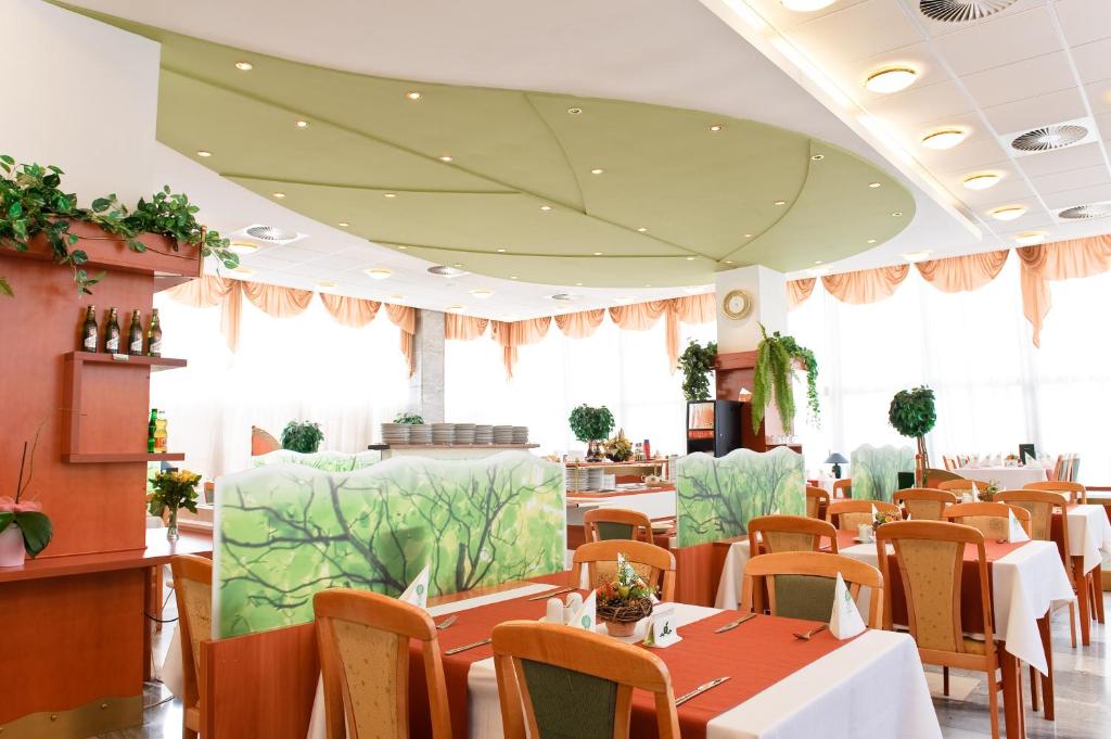 特伦钦温泉镇Hotel Flóra的用餐室设有桌椅和窗户。