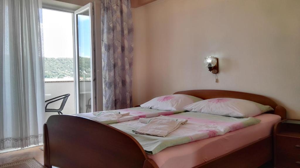 拉布Ljubica Apartments and Rooms的一间卧室配有一张带粉色床单的床和一扇窗户。