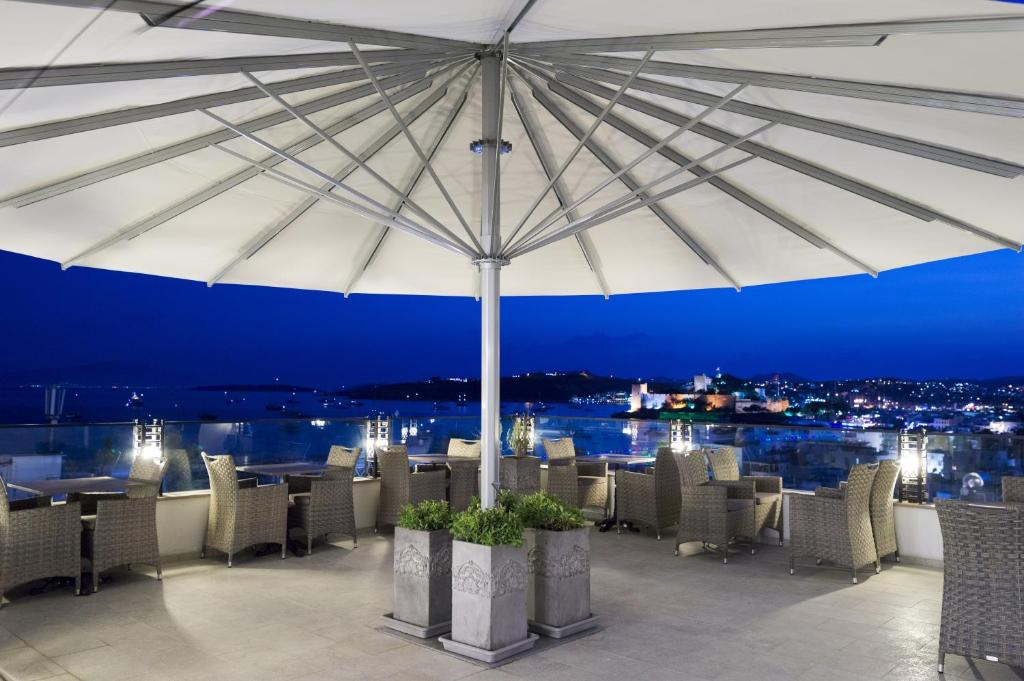 博德鲁姆艾纳精品酒店的一间带遮阳伞和桌椅的餐厅