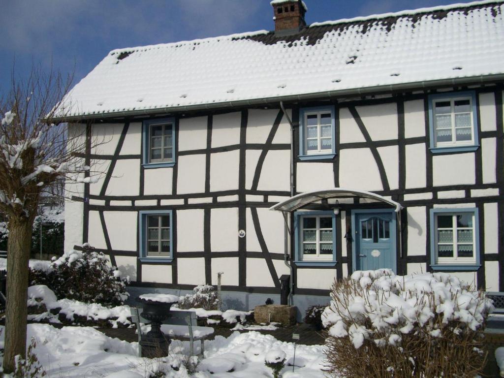 布兰肯海姆Haus-Hoeppches的雪中带蓝色门的白色房子